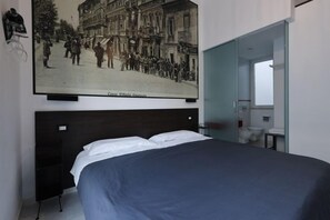 A bedroom with a bed, a large poster of a historical street scene, and a glass door leading to a bathroom. - Ok Home Pescara Rooms (Pescara)