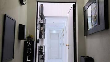 A hallway with a 'WELCOME' sign, a door at the end, and a staircase leading to another floor.