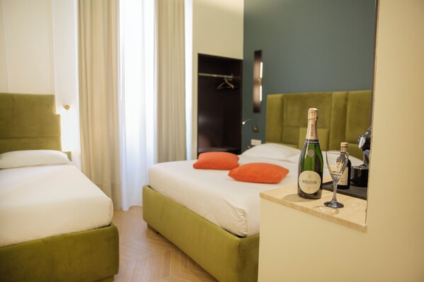 A hotel room with a bed, a bedside table with a bottle and glass, and a green headboard. - Unicum Trastevere Suites (Rome)