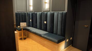 A modern waiting area with a bench, a laptop on a small table, and a door.