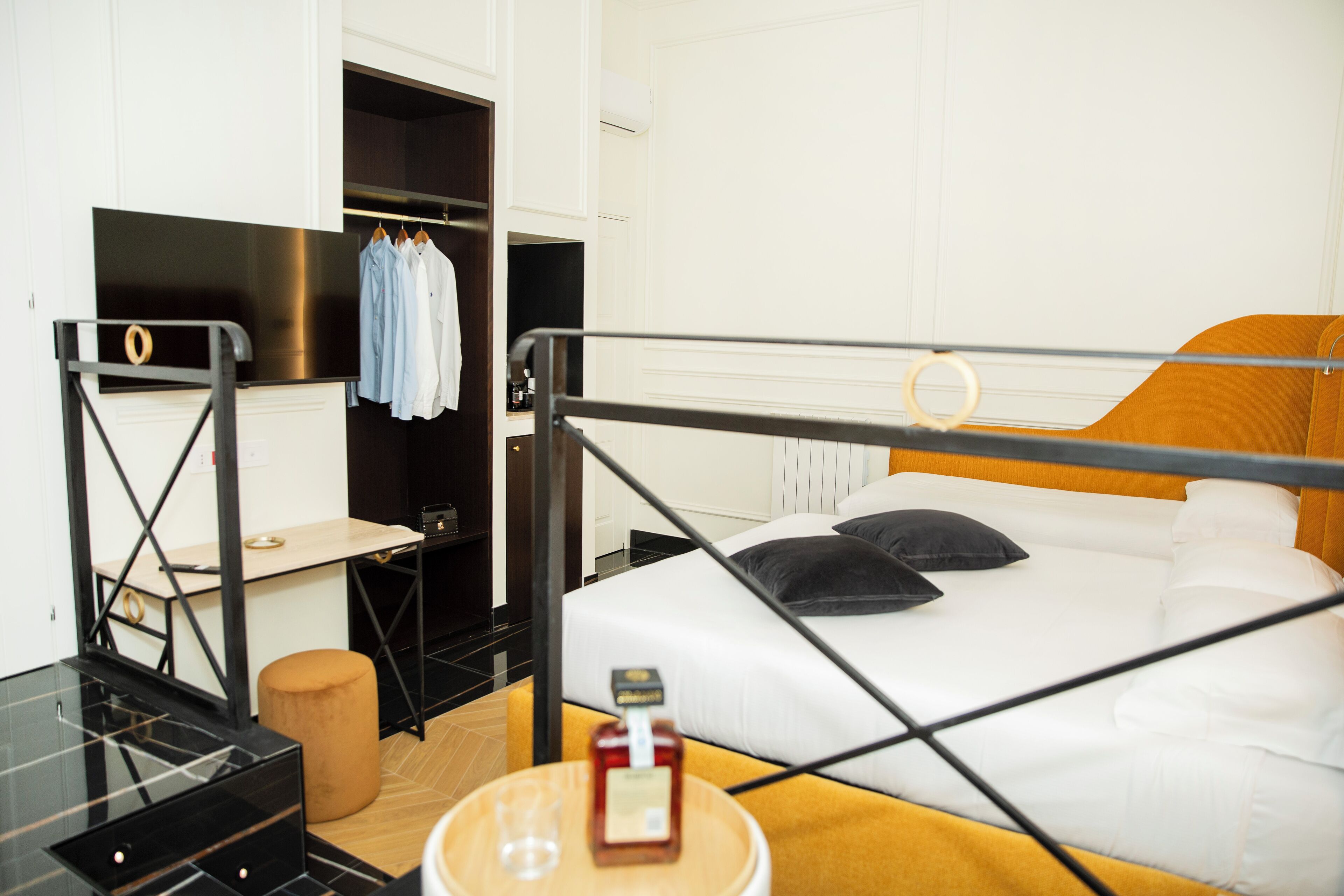 A modern hotel room with a bed, a small table, a chair, a desk, and a wardrobe.