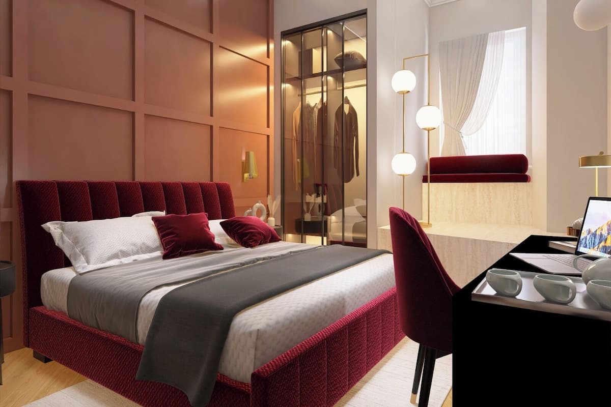 A modern bedroom with a large bed, a desk with a laptop, and a walk-in closet.