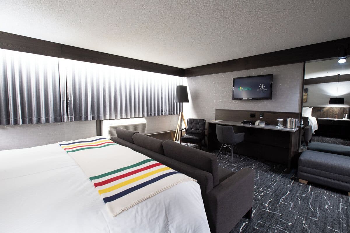 A hotel room with a large bed, a sofa, a desk, and a TV.