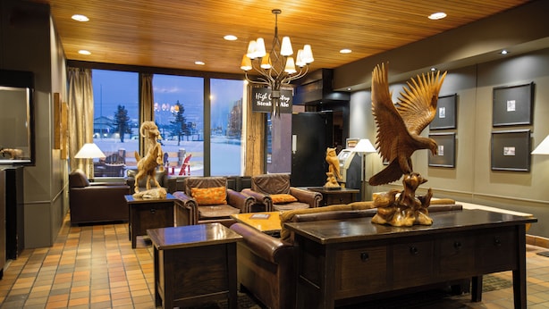 A spacious living area with a large wooden coffee table, leather sofas, and a chandelier. - Grande Cache Hotel (Grande Cache)