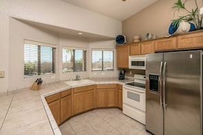 A modern kitchen with wooden cabinets, a stainless steel refrigerator, and a built-in oven. - Downtown Pool Home and boat parking (Lake Havasu City)