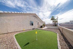 A building with a flat roof, a paved area with artificial grass, and a clear sky. - 5 Bedroom, Pool Home w/ Spa, Putting Greens & Near London Bridge (Lake Havasu City)