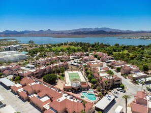 An aerial view of a resort with multiple buildings, a tennis court, and a swimming pool.