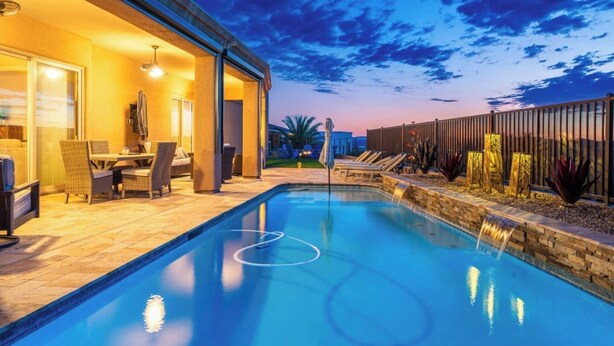 Une piscine agrémentée d’une cascade, un espace salon extérieur et une terrasse.