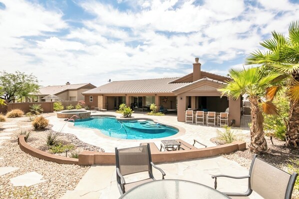 A residential property with a swimming pool, outdoor seating, and a patio area.