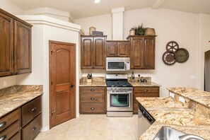 A kitchen with wooden cabinets, granite countertops, stainless steel appliances, and a built-in oven.