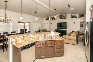 A spacious kitchen with a central island, wooden cabinets, and a built-in dishwasher.