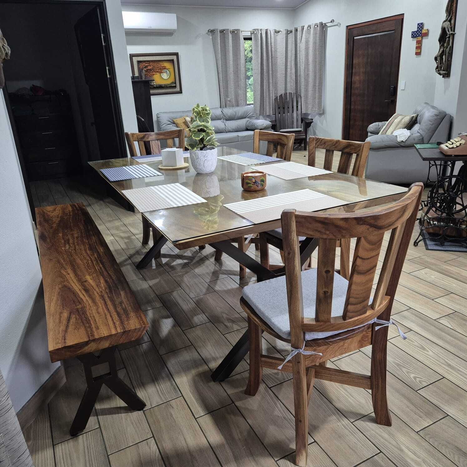 Un coin repas avec une table à plateau en verre, des chaises en bois et un banc.