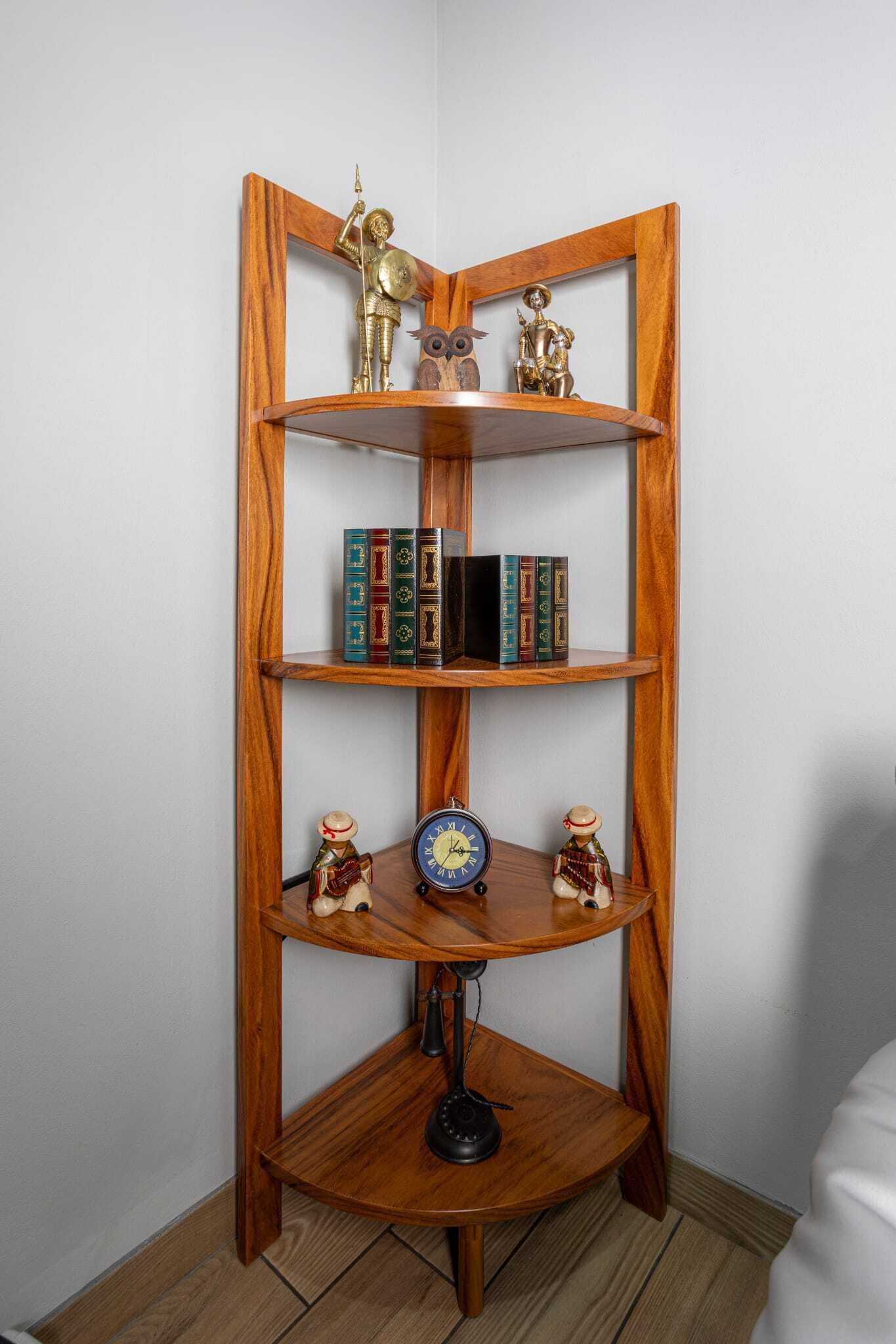 Ein hölzernes Eckregal mit Dekoration und Büchern.