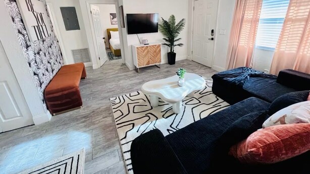 A modern living room with a sofa set, a coffee table, and a TV mounted on the wall. - Miami Art Deco Vibes • Stay Near Downtown (Tampa)