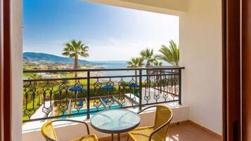 Enjoy a serene view of the pool and surrounding landscape from this balcony, featuring a small table and two chairs.