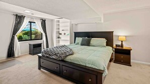 Un dormitorio con cama, mesita de noche, lámpara, ventana con cortinas y estante con objetos decorativos.