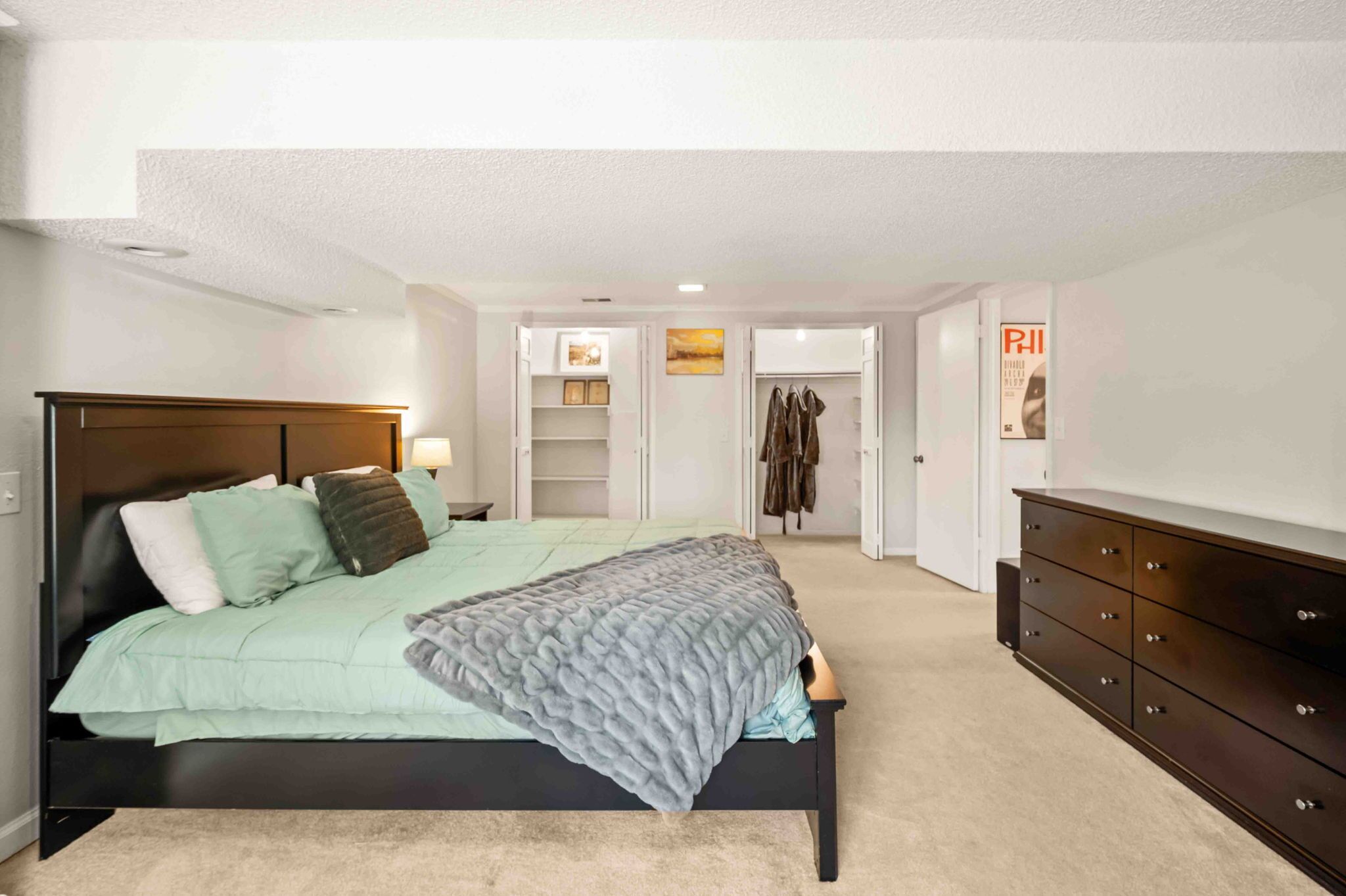 A bedroom with a bed, a dresser, a closet, and a walk-in closet.