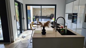 Una cocina moderna con una isla central, horno empotrado y un amplio ventanal con vistas a un patio.