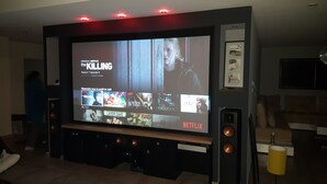 Sistema de cine en casa con una pantalla grande mostrando la interfaz de Netflix.