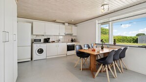 Una cucina moderna con mobili bianchi, un tavolo da pranzo con sedie e vista sul verde circostante.