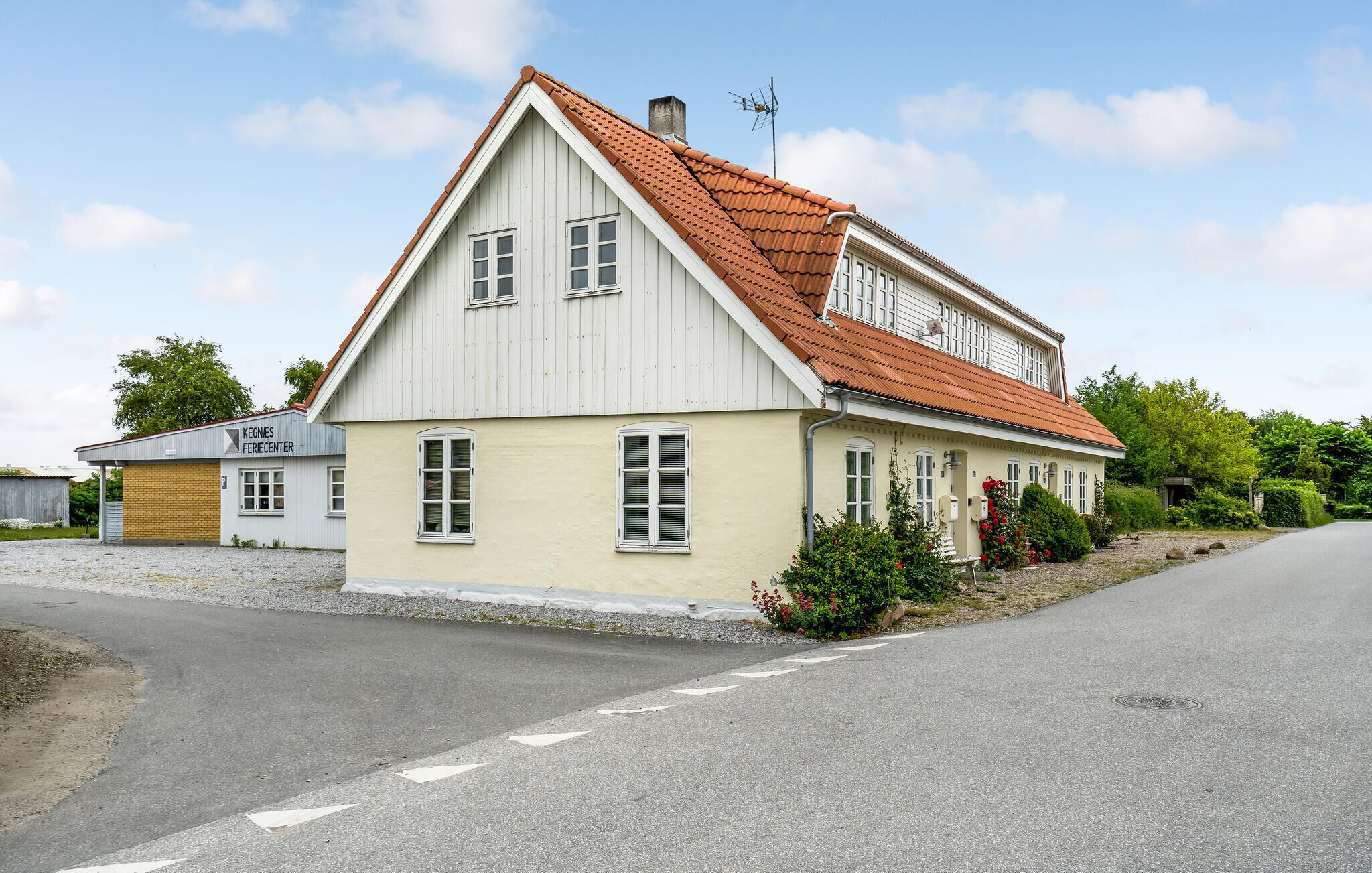 Un bâtiment à deux étages, doté d’un toit à pignon et d’une cheminée, situé à côté d’une route.