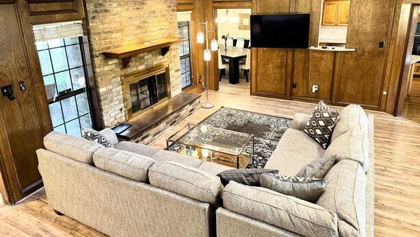 A spacious living room with a fireplace, a large sofa, and a flat-screen TV. - Cozy Pool Home Designed for Both Family Fun & Serenity (Plano)