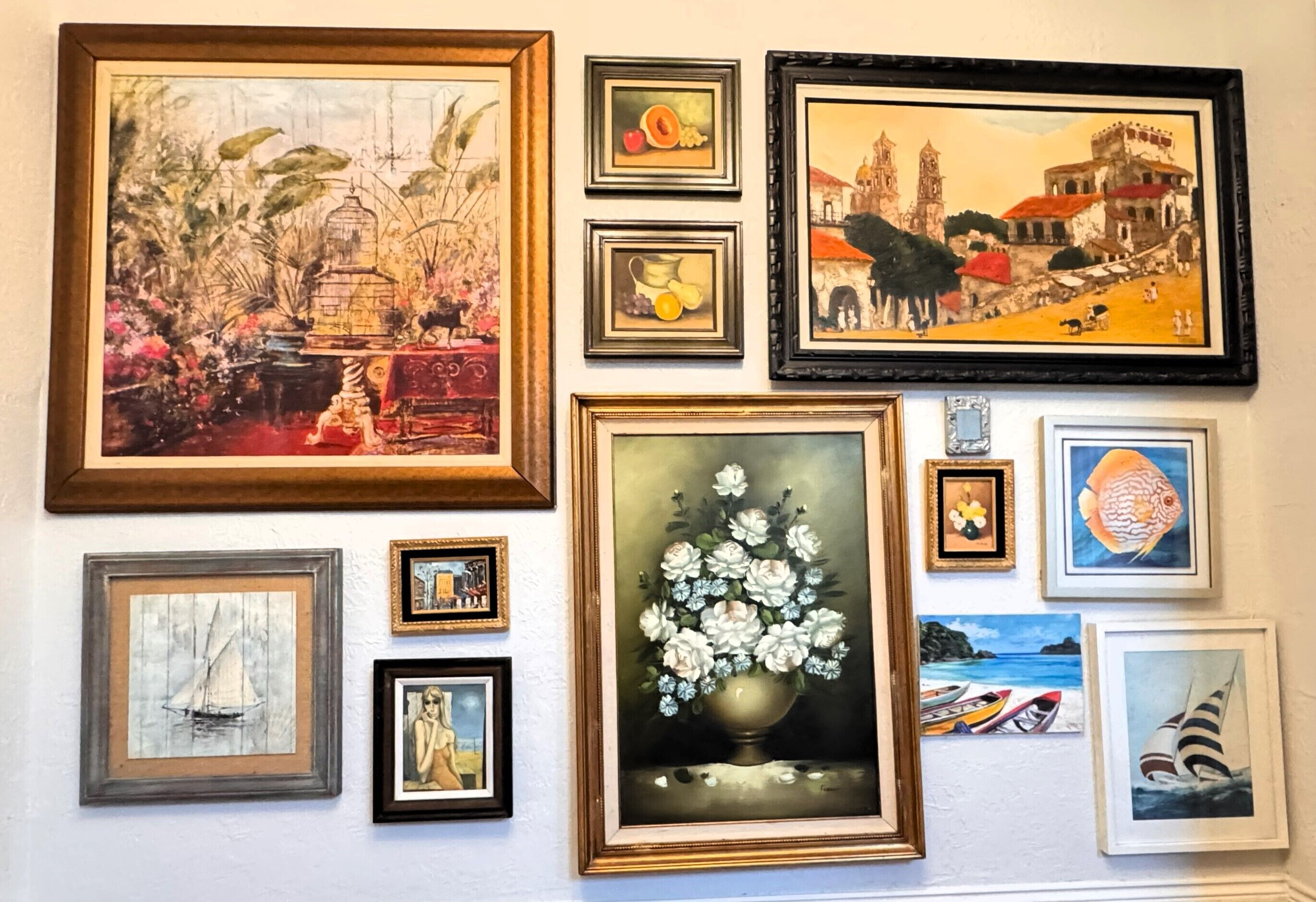 A wall with various framed artworks including paintings and prints.