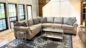 A modern living room with a sectional sofa, a coffee table, and a patterned rug. - Cozy Pool Home Designed for Both Family Fun & Serenity (Plano)
