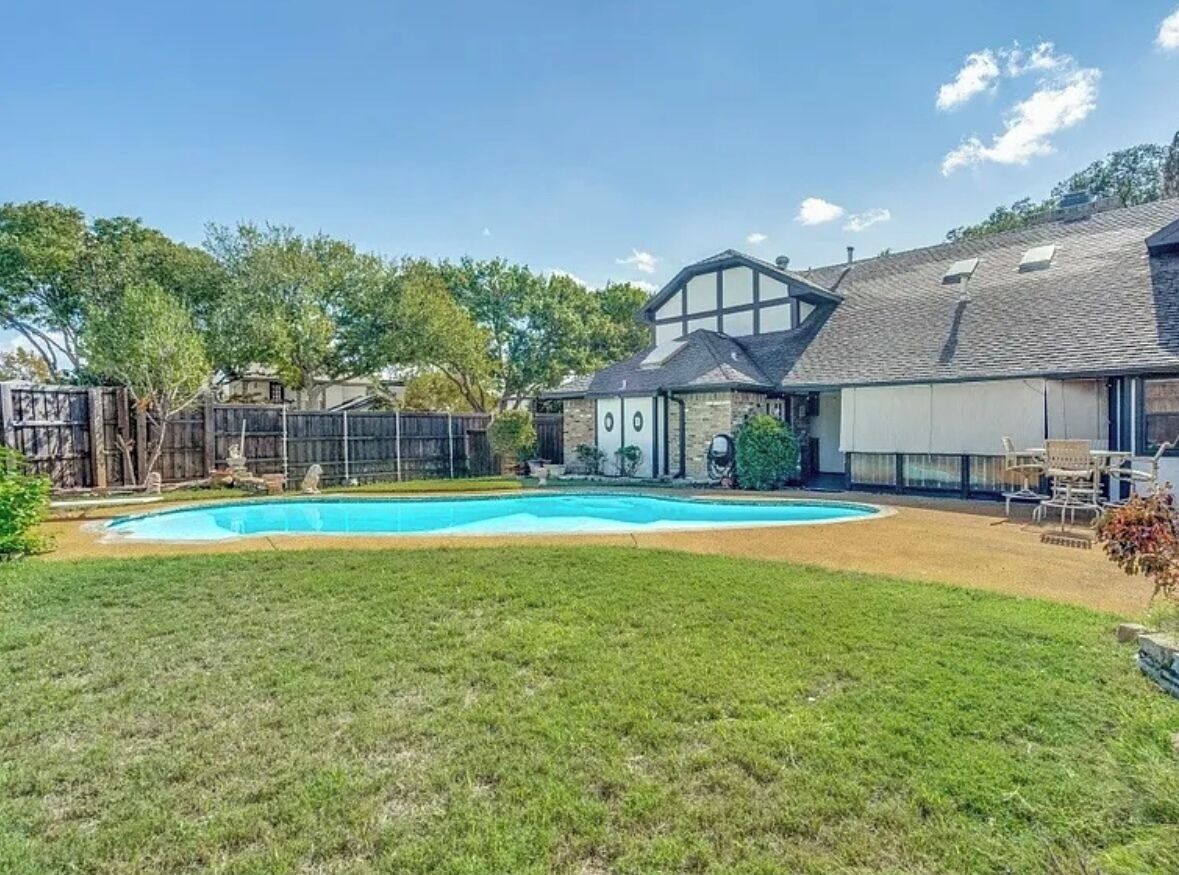 Ein Garten mit Schwimmbad, einem eingezäunten Bereich und einem Haus mit Garage.