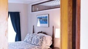 Une chambre à coucher avec un lit, une table de chevet, une lampe et un tableau encadré au mur.