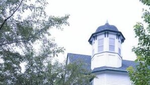 Un bâtiment blanc doté d’une tour et d’un patio couvert avec des chaises en métal.