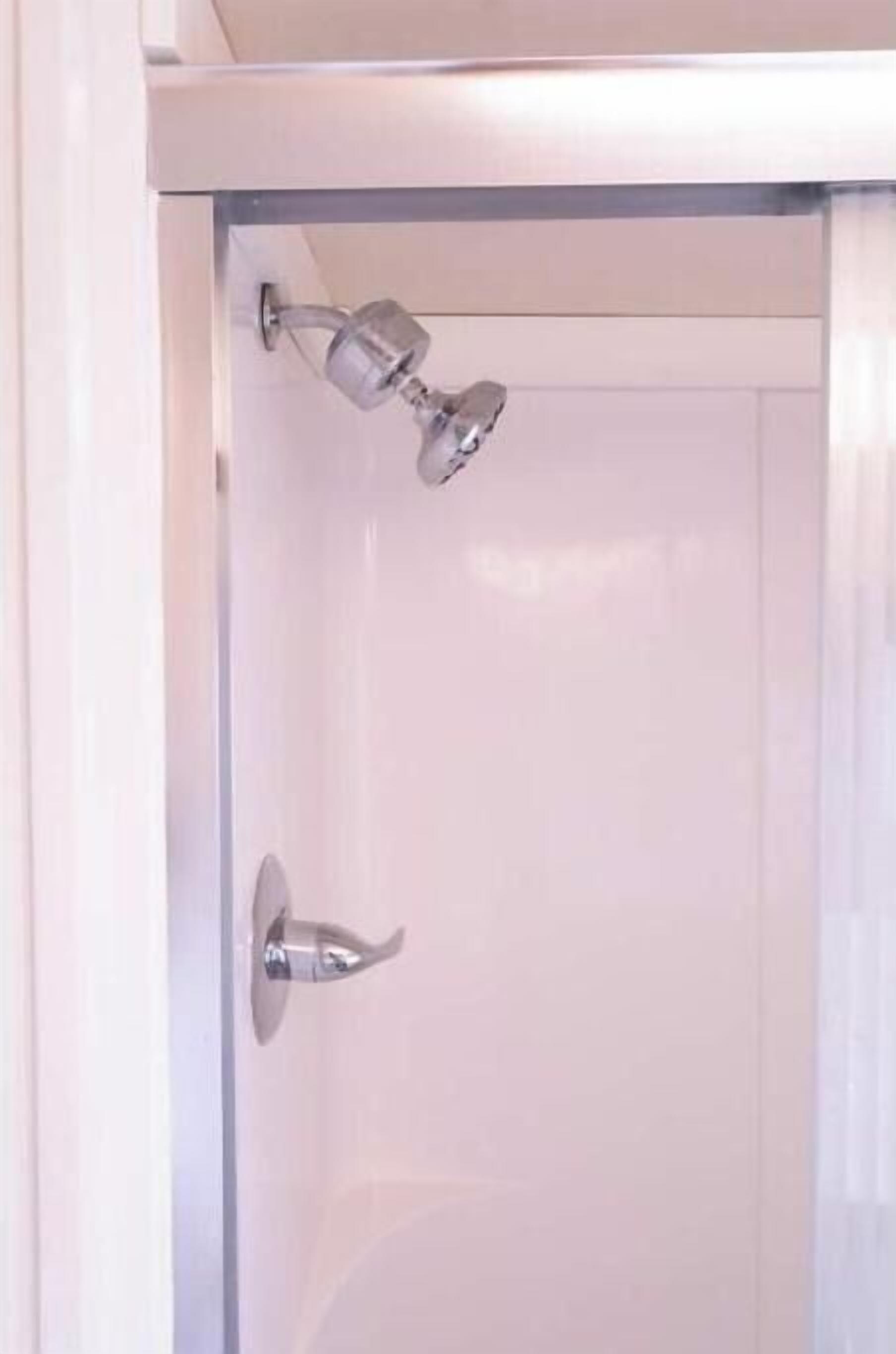 Eine weiße Duschkabine mit Handbrause und am Wand befestigtem Wasserhahn.