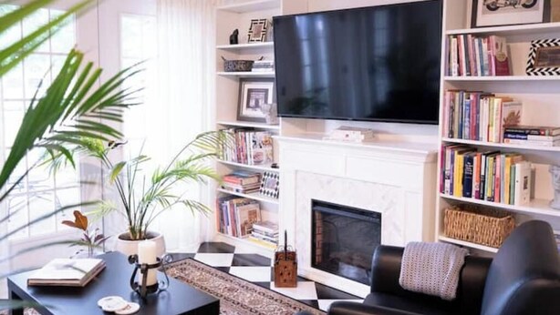 Een woonkamer met een open haard, een televisie en boekenkasten.