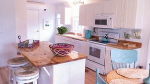 Una cocina con armarios blancos, una isla de madera y una silla azul.
