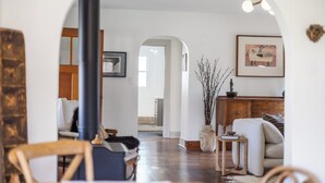 A cozy living room with a wooden floor, a fireplace, and a view through an archway to a bathroom.