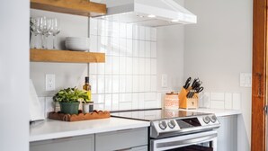A modern kitchen with white cabinetry, a built-in oven, and a stainless steel stovetop.