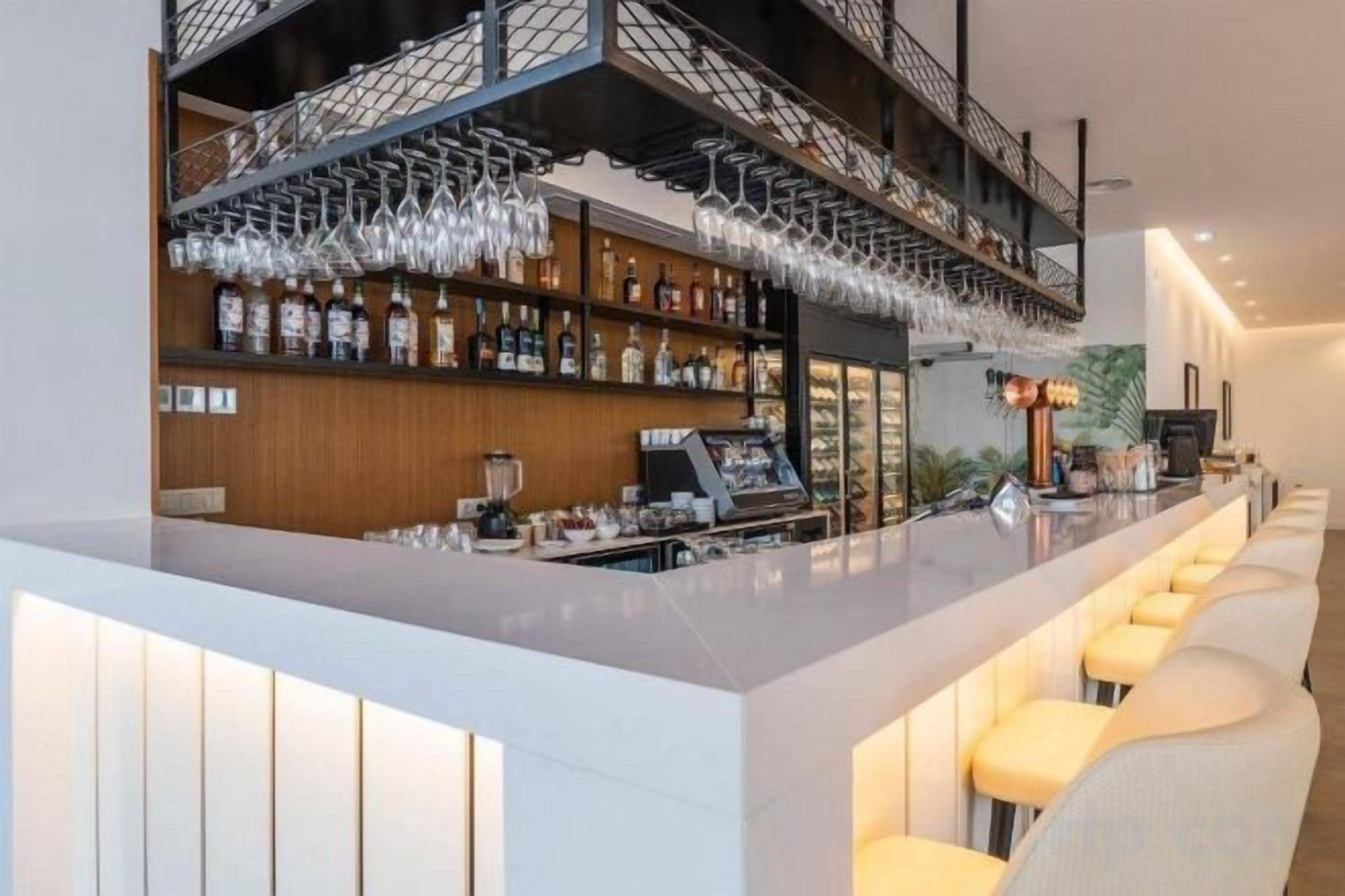 A bar area with a long counter, bar stools, and shelves stocked with bottles.