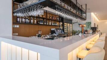 A bar area with a long counter, bar stools, and shelves stocked with bottles.