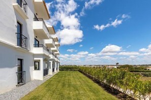 Ein modernes Gebäude mit mehreren Balkonen, einem gepflegten Rasen und blauem Himmel.