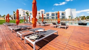 A resort with a wooden deck, sun loungers, and umbrellas.