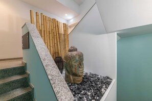 A staircase with a stone wall, a bamboo wall, and a Buddha statue. - Regency Salgados Hotel & Spa (Guia)