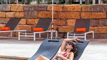 A poolside area with lounge chairs and a stone wall.
