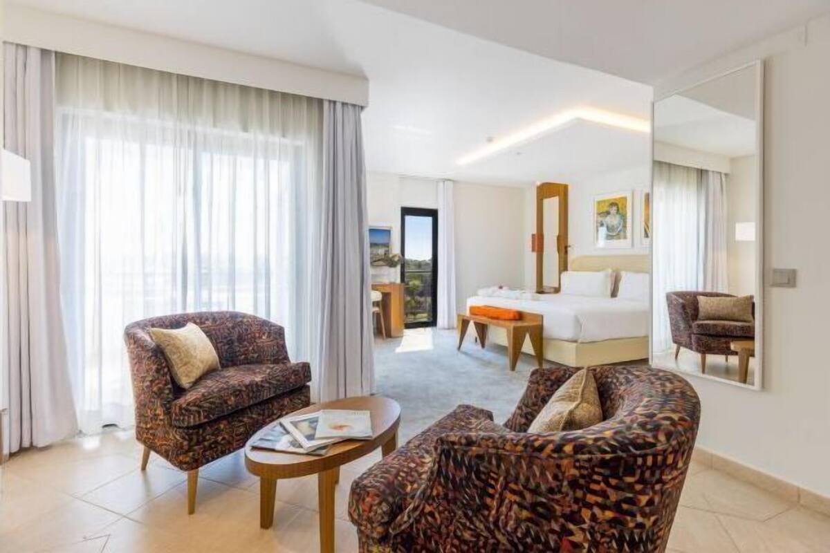 A hotel room with a bed, a sofa, a coffee table, and a large mirror.