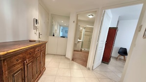 Cocina moderna con encimera y armarios de madera, cabina de ducha de vidrio y un pasillo que conduce a un dormitorio.
