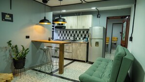 A compact kitchen with a central island, bar stools, and a green sofa. - Exceptional Marinilla Apartment (Marinilla)