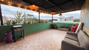 A covered patio with a grill, outdoor furniture, potted plants, and a view of the cityscape. - Exceptional Marinilla Apartment (Marinilla)