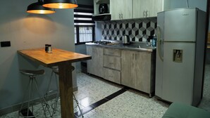 A compact kitchen with a wooden table and stools, a stainless steel refrigerator, and a tiled backsplash. - Exceptional Marinilla Apartment (Marinilla)