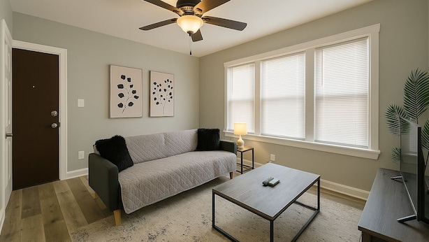 A living room with a sofa, coffee table, ceiling fan, and artwork on the wall.