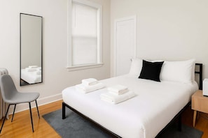 Relax in a spacious room with a large bed, bedside table, and comfortable chair.