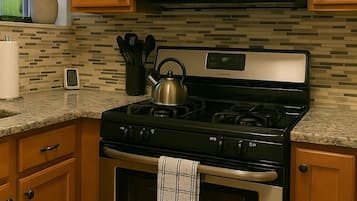 A kitchen with wooden cabinets, a stainless steel stove, a microwave, and a tiled backsplash.